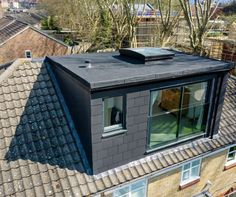 an aerial view of a roof with windows and a flat - roofed building in the background