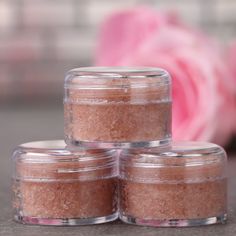 three jars filled with brown sugar sitting on top of a table next to a pink rose