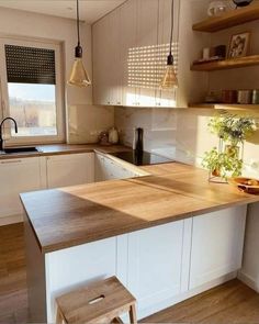 a kitchen with white cabinets and wooden counter tops, two stools in front of the island