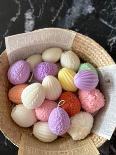 a basket filled with lots of different colored soaps next to an open book on a table