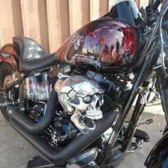 a motorcycle with skulls painted on it parked in front of a fence and wooden slats