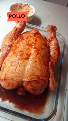 a chicken sitting on top of a glass pan covered in ketchup and sauce