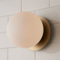 a light that is on the side of a white tile wall next to a tiled floor