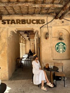 a woman sitting at a table in front of a starbucks