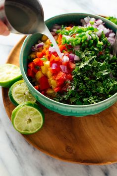 a person pouring dressing into a bowl filled with vegetables and garnished with cilantro