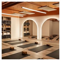 an empty yoga room with rows of mats on the floor and shelves full of books