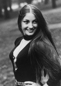 black and white photograph of a young woman with long hair wearing a sweater smiling at the camera