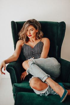 a woman sitting in a green chair with her legs crossed