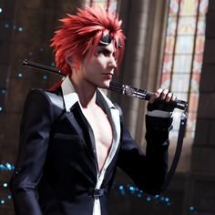 a man with red hair holding a microphone in front of a stained glass window and wearing a black suit