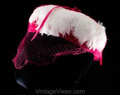 "This dome-shaped 1960s spring hat is a soft layer of thick white feathers over a base of vivid pink velvet, so charming and coy with a \"cage\" of veiling. Measurements 20 3/8 Inches Circumference at inside base of crown, approx Height 3 Inches Era 1960s Label Union label to inside back Materials White feathers, shocking pink synthetic velvet and matching diamond pattern net, matching pink stiff buckram frame Closure None needed Condition Good Condition Detail Barely worn, the netting has 6-8 s Retro Pink Brimmed Hat, Pink Fitted Cap Mini Hat, Vintage Pink Mini Hats For Vintage Events, Pink Vintage Mini Hats For Vintage Events, Pink Retro Party Hats, Vintage Pink Mini Hat For Party, Vintage Pink Fitted Fascinator, Vintage Pink Fascinator For Kentucky Derby, Pink Vintage Fascinator For Kentucky Derby