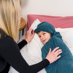 a woman in black shirt laying on top of a bed next to a little boy