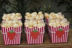 four red and white striped boxes with strawberries on them sitting on a wooden table