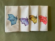 four napkins with butterfly designs on them are lined up in a row against a green wall