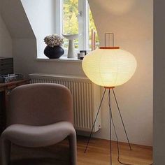 a lamp sitting on top of a wooden floor next to a chair in a room