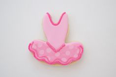 a cookie decorated with pink and white polka dots on a plain surface, the shape is shaped like a ballerina's tutuff