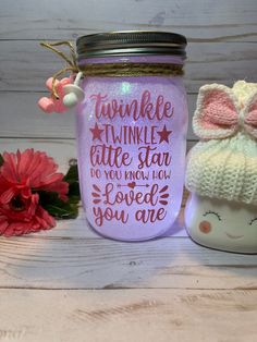 a mason jar with a knitted hat on it next to a pink flower vase