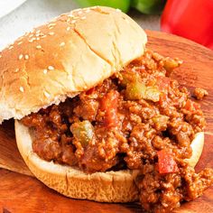 a sloppy joe sandwich sitting on top of a wooden cutting board