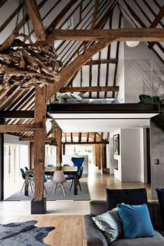 a living room filled with furniture next to a tall wooden ceiling covered in wood beams