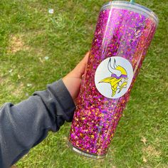 a hand holding a purple and yellow glittered tumbler