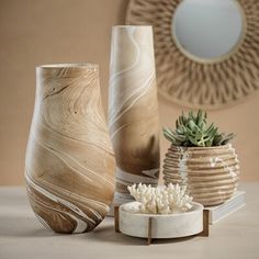 three vases sitting on top of a table next to a mirror and planter