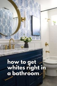 a white toilet sitting next to a blue vanity in a bathroom under a round mirror