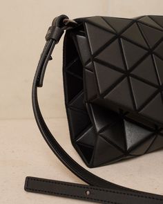 Tonneau bag by Bao Bao Issey Miyake in matte black. Small crossbody purse with characteristic barrel shape and trademark tessellating triangular. Elegant leather-like finish with cowhide trims at the adjustable strap. Flap closure with magnetic clasp and zipped compartment to elegantly contain essentials. Synthetic Leather, Polyester, Nylon.Made in Japan. Luxury Triangle Evening Bag, Luxury Triangle Evening Bags, Modern Triangle Shoulder Bag For Evening, Geometric Leather Shoulder Bag For Evening, Modern Triangle Shoulder Bag For Evenings, Modern Triangle Bag With Detachable Strap, Geometric Leather Evening Bag, Modern Geometric Shoulder Bag With Adjustable Strap, Modern Black Geometric Bags