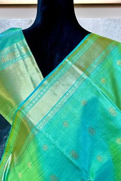 This exclusive regal kanjivaram silk saree inpista green shot with pastel blue is handwoven with close knit vaira oosi stripes. The body is adorned with iruthalai pakshi and chakram buttas in gold zari. The grand 2 sized borders in geometric and traditional motifs in gold zari is nothing but a treat to the eyes. The grand pallu mimics the borders featuring traditional motifs in gold zari. Royal addition to your collection Approximate Length 6.5 mtrs (inclusive of blouse length) Approximate Height - 48 - 52" Approximate weight - 1.7 lbs Saree comes with fall, picot and tassels done when applicable. Blouse piece is cut. Kindly Note : The colors you see on your device may vary due to the color reproduction, brightness and resolution of individual devices. If you'd like more clarity before you Green Pre-draped Saree With Zari Weaving In Dola Silk, Pista Green Tussar Silk Saree With Zari Weaving, Turquoise Silk Saree With Zari Weaving, Pista Green Silk Pre-draped Saree With Zari Weaving, Green Pre-draped Tussar Silk Saree With Zari Weaving, Green Shot, Kanjivaram Silk Saree, Silk Cotton Sarees, Traditional Motifs