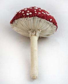 a red and white mushroom sitting on top of a white table next to a knife