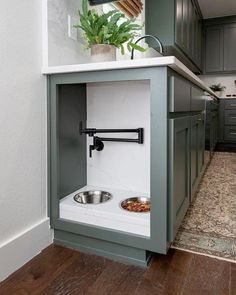 a dog bowl in the corner of a kitchen with green cabinets and white counter tops