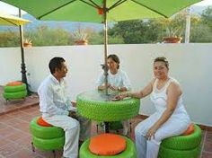 three people sitting at a table with green chairs and umbrellas on top of it