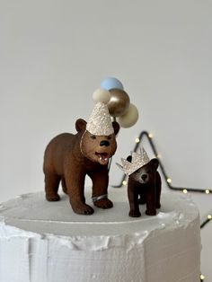 there is a cake that has two bears on it and one bear wearing a party hat