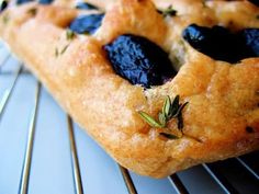 a piece of bread with olives on it sitting on top of a cooling rack