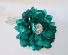 a close up of a green flower on a white surface with diamond brooches