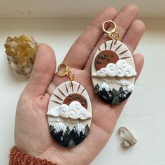 two handmade earrings with mountains and clouds on them