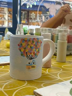 there is a coffee mug with a tree on it sitting on the table next to other cups