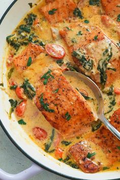 a pan filled with salmon and spinach covered in sauce