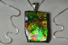 This raw ammolite necklace features a fabulous ammolite gemstone in it's natural form. The ammolite has a piece of slate attached to the back for stability and an epoxy coating on the surface for protection. The ammolite was mined in Alberta, Canada which is known for producing the best quality ammolite in the world!  The ammolite measures 23.5x17.5mm not including the sterling silver bail.  The 18" necklace is also made of sterling silver.   This item will be sent in a high end wood pendant box Ammolite Jewelry, Natural Form, Epoxy Coating, Wood Pendant, Alberta Canada, Natural Forms, Necklace Sterling Silver, Green Orange, Sterling Silver Pendant