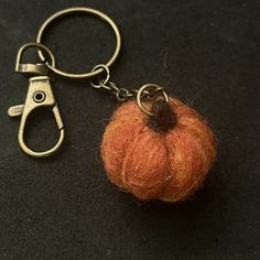 a needled pumpkin keychain with a pair of scissors hanging from it's end