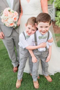 two young boys are standing next to each other in front of the bride and groom