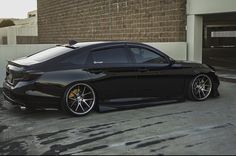 a black sports car parked in front of a brick building with yellow rims on it