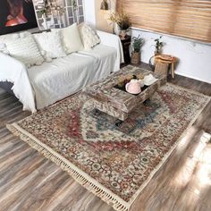 a living room filled with furniture and a rug on top of a hard wood floor