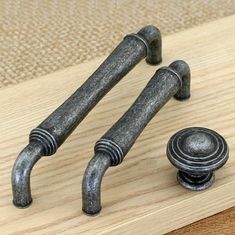 two metal handles and knobs on a wooden surface with a rug in the background