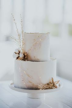 two tiered white wedding cake with dried flowers on top