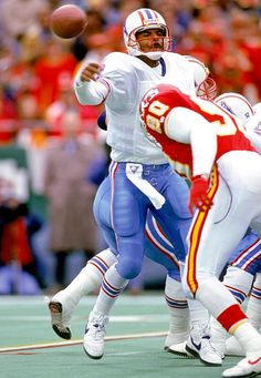 a football player throwing a ball in front of two other players on the sidelines