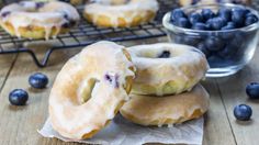 blueberry donuts are stacked on top of each other next to a bowl of blueberries