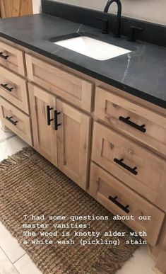 a bathroom vanity with black counter top and wooden cabinetry on the floor next to a white wash basin