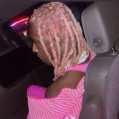 a woman with pink dreadlocks sitting in a car