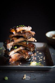 some meat is stacked on top of each other in a black tray with sauce and seasoning