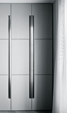 a tall stainless steel refrigerator freezer sitting in a kitchen next to a white curtain