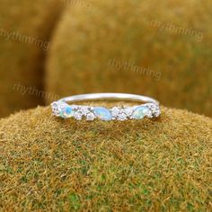 an opal and diamond ring on top of moss